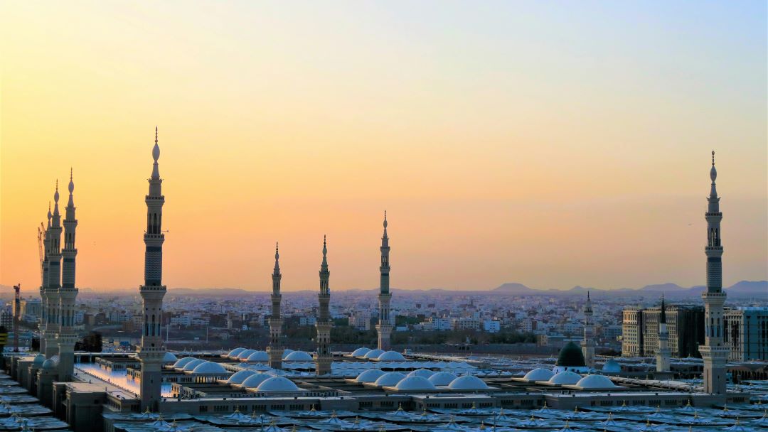 Vy över orientalisk stad med minareter mot solnedgångshimmel